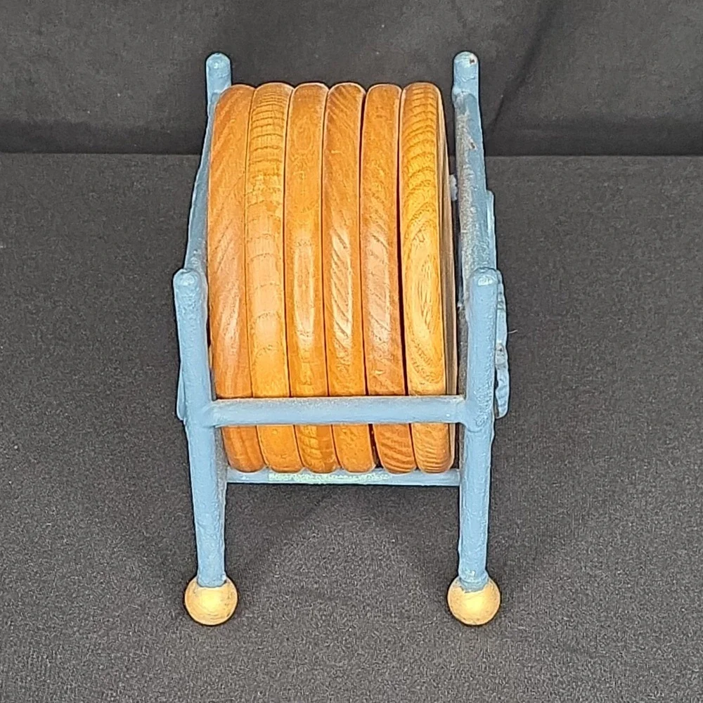 a vintage wooden drink coasters in a blue metal  holder with leaf-shaped accents